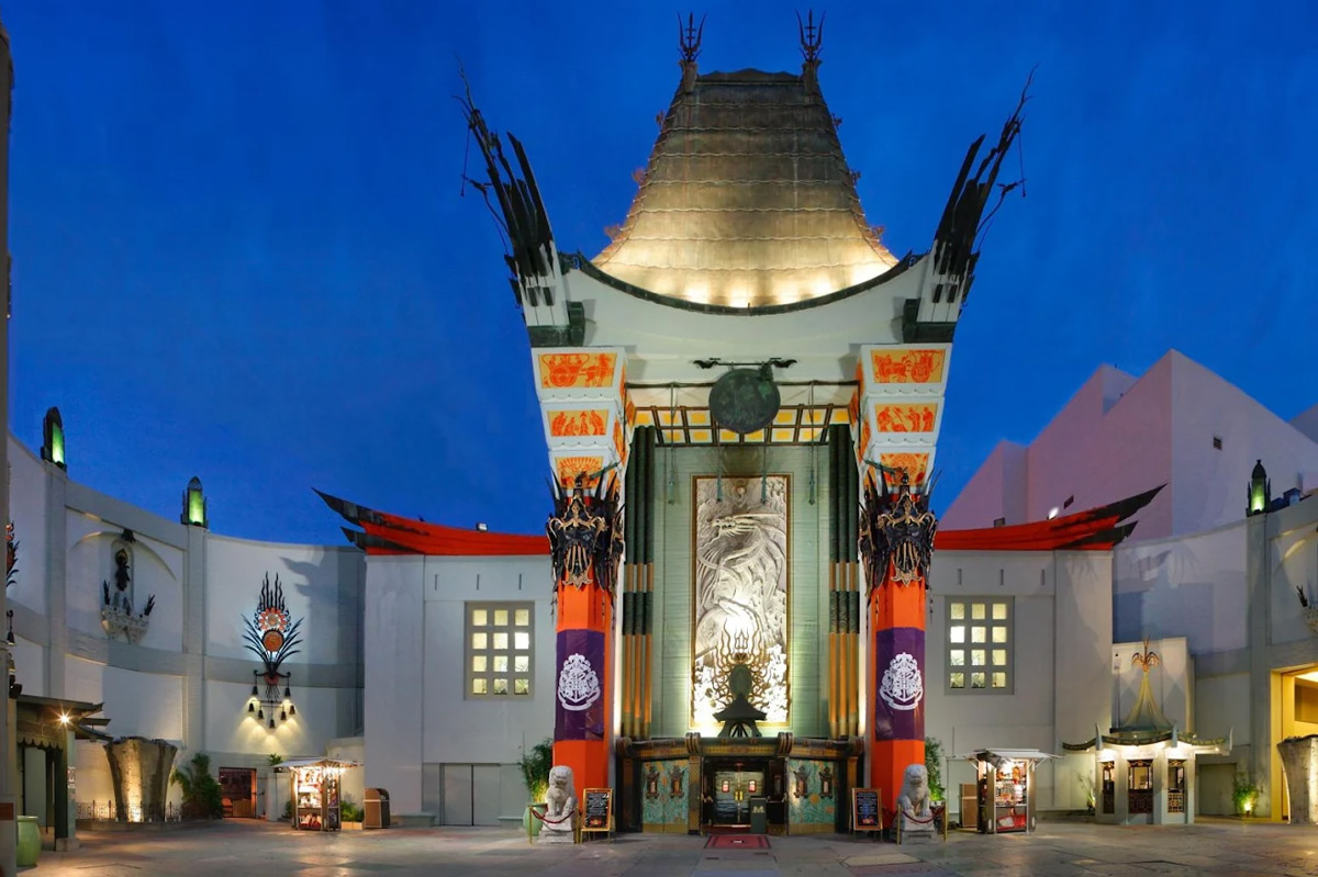 An ornate theater entrance features Asian-inspired architecture, colorful decorations, and illuminated architectural elements against a twilight sky.