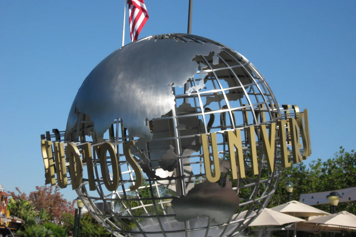 A metallic globe structure with an American flag, showcasing the name 'Universal' in gold letters against a blue sky.